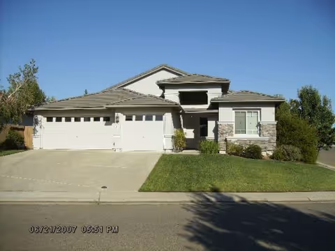 Front exterior of a modern single-story home with a three-car garage and lawn