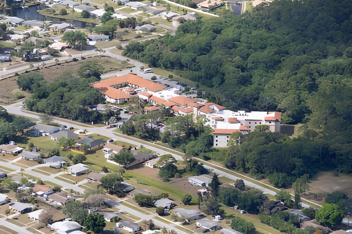 Aerial view of Discovery Commons South Biscayne facility surrounded by dense green trees and residential houses with roads connecting the area.