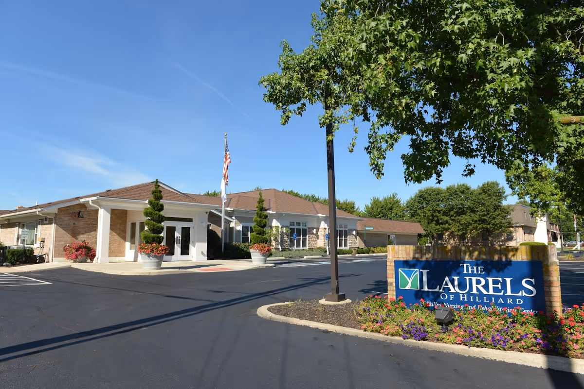 The entrance of The Laurels of Hilliard senior living facility showcasing landscaped surroundings and a sign.