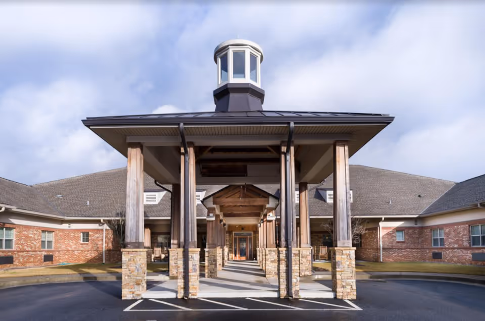 Front entrance of a memory care facility with a covered porte-cochère and brick walls.