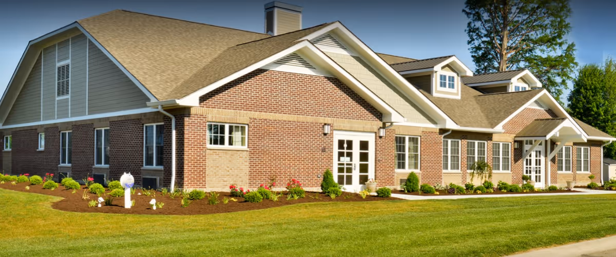 Single-story brick building with gabled roofs, landscaped flowerbeds and a manicured lawn in front.
