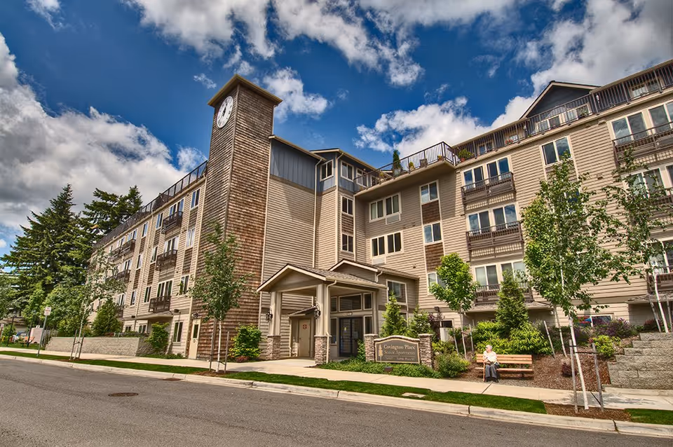 Exterior view of Covington Place Senior Apartments with clock tower and landscaping.