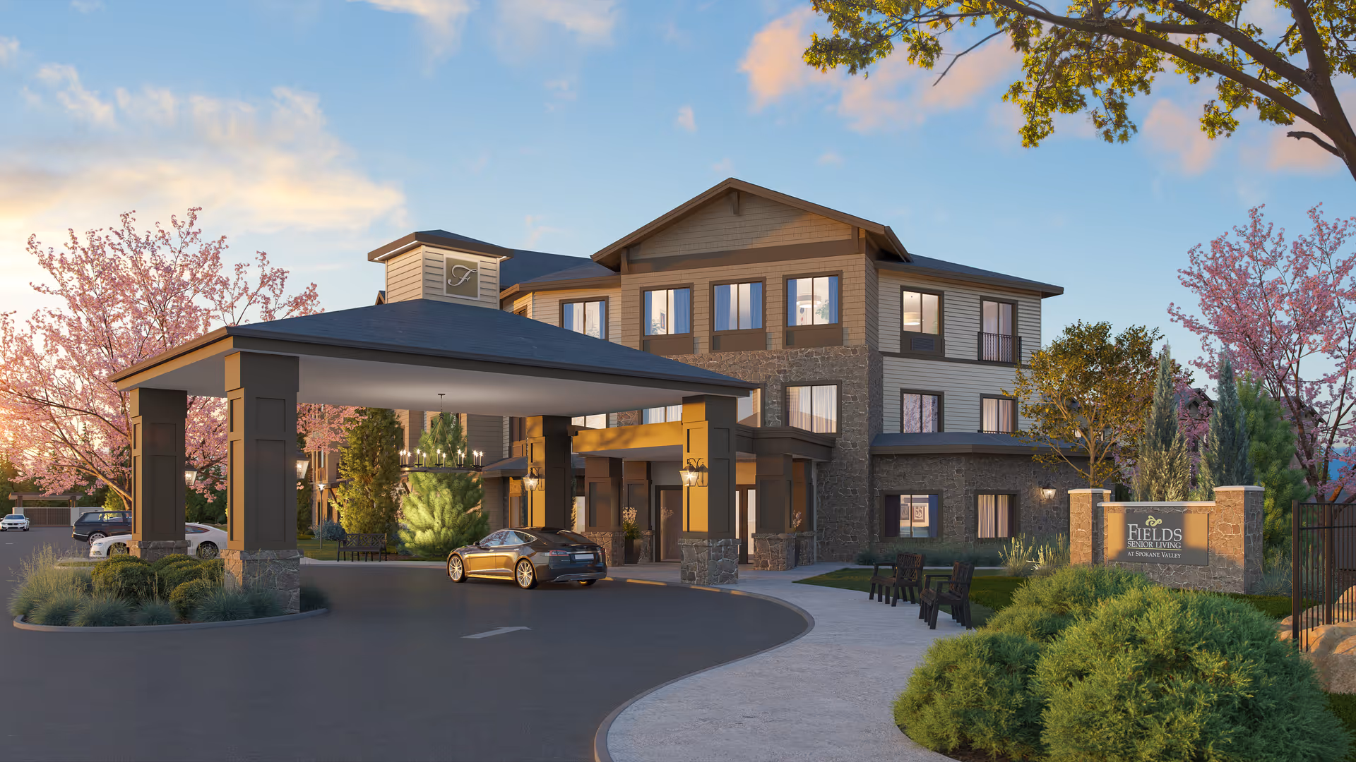 Front exterior of Fields Senior Living at Spokane Valley showing a three-story building with a covered porte-cochere, driveway, and landscaped grounds.