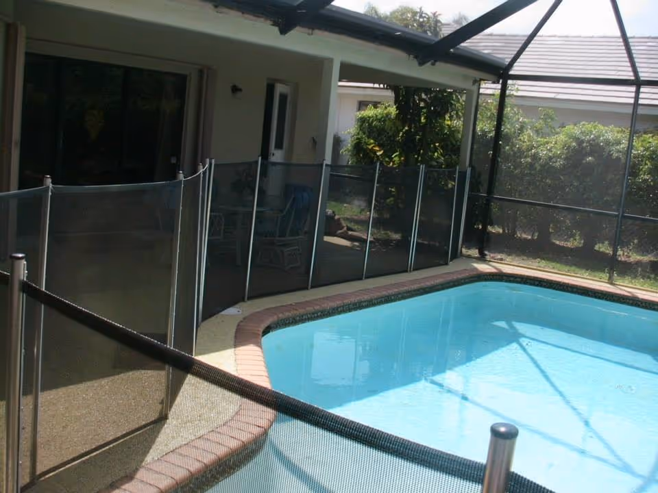 Enclosed outdoor pool area at Sunshine Assisted Living with seating and screened fencing.