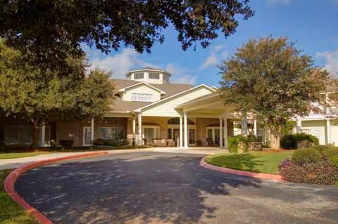 Exterior view of The Waterford on Huebner building with driveway and trees.