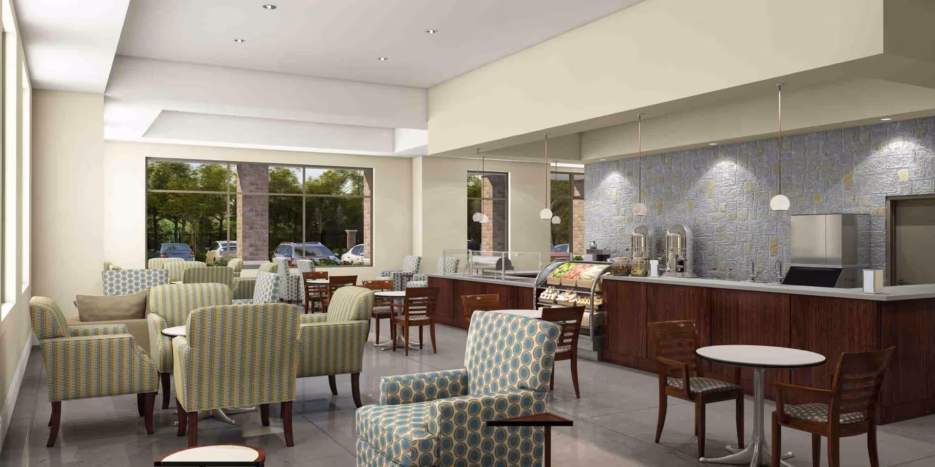 A bright and modern dining area with patterned armchairs and wooden chairs around small round tables. There is a serving counter with food displays and beverage dispensers against a stone-textured wall. Large windows allow natural light to fill the space and show parked cars and trees outside.