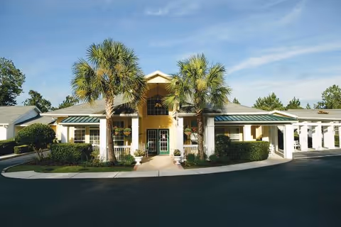 Front view of The Gables of Gainesville building with palm trees and entrance.