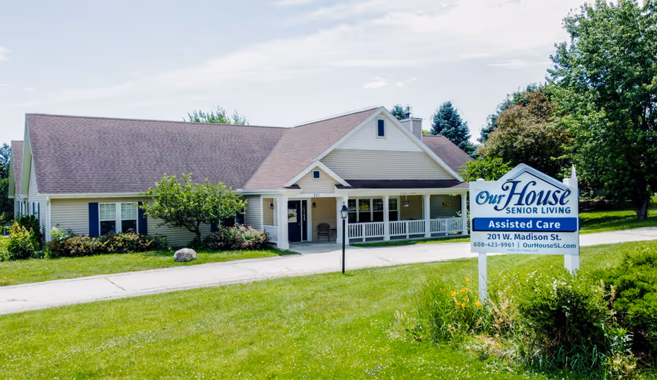Front exterior of a single-story senior living building with a lawn and a prominent sign reading 'Our House Senior Living - Assisted Care'.