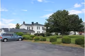 Exterior view of Living Waters senior facility with parking, bushes, and trees in front.