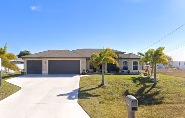 Single-story senior living facility exterior with a three-car garage, driveway, and palm trees.