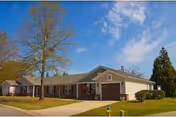 Front view of Wesley Commons senior living facility with driveway, lawn, and trees.