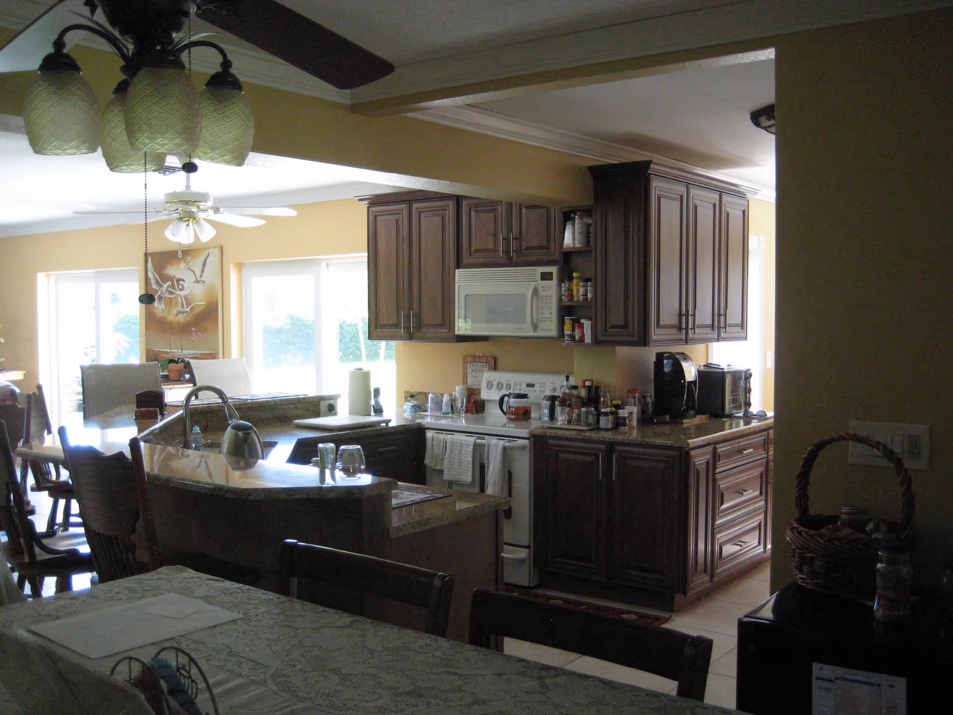 Open-plan kitchen with dark wood cabinets, a microwave and stove, an island countertop and an adjacent dining area.
