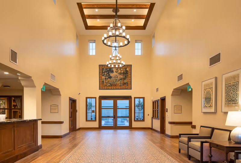 Bright lobby with chandeliers, wooden floors, and glass double doors.