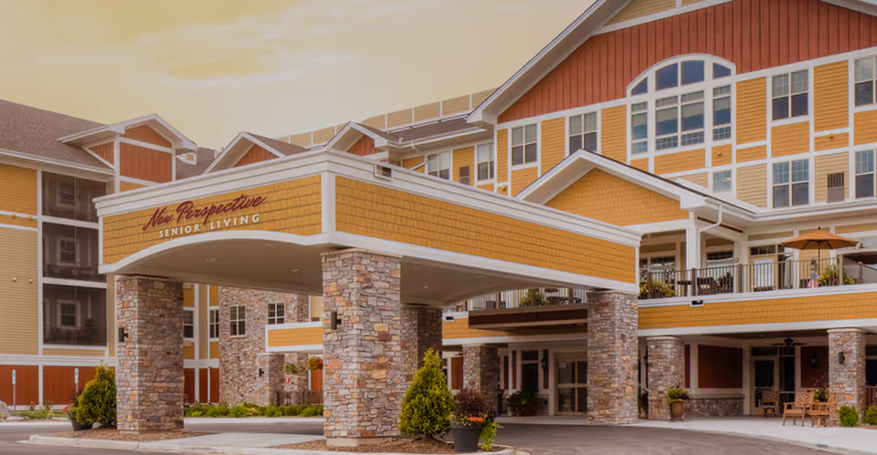 Exterior view of New Perspective Senior Living Sun Prairie entrance with yellow facade