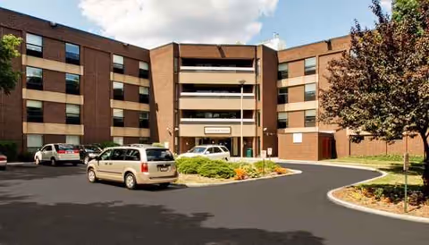Exterior view of Maplewood Rehabilitation and Nursing Center with a circular driveway and parked cars.