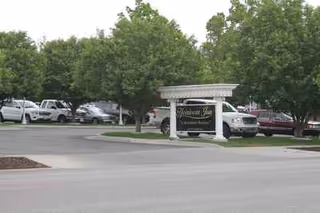 Exterior view of Heirloom Inn entrance with trees and parked cars.