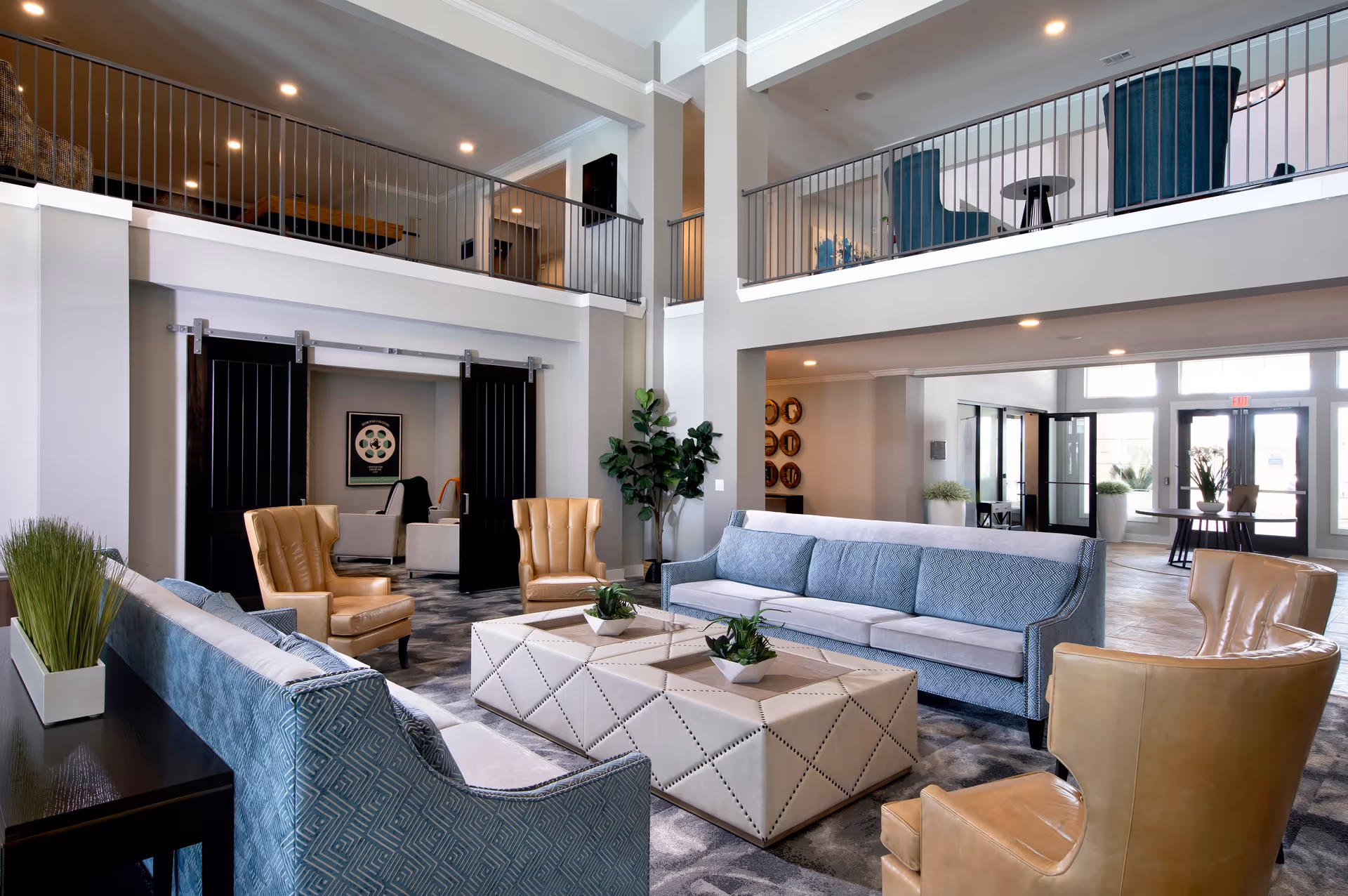 Spacious two-story lounge with sofas, armchairs, coffee tables, and an upper balcony overlooking the seating area.