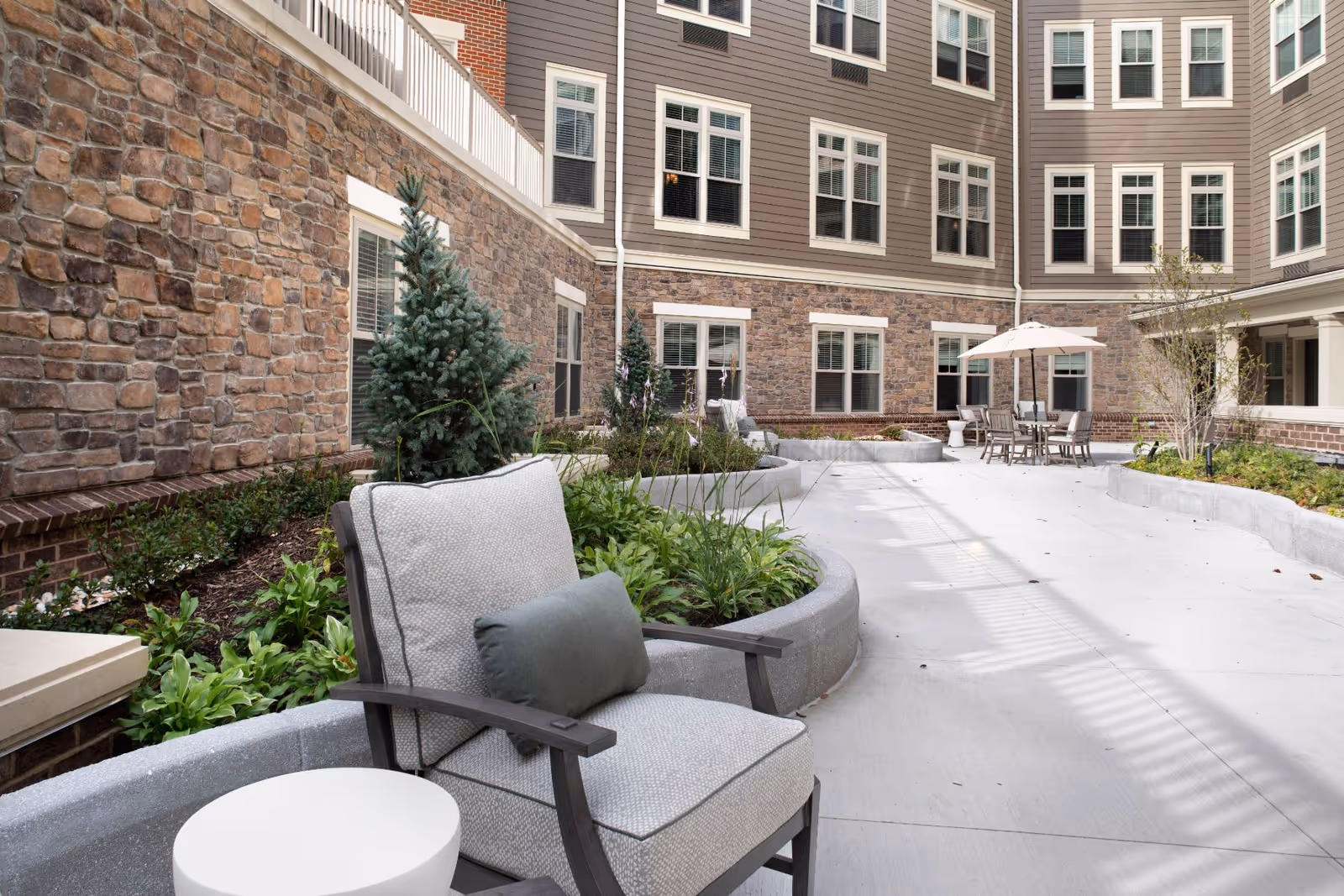 Outdoor courtyard with patio seating, planters, and a multi-story building surrounding it.