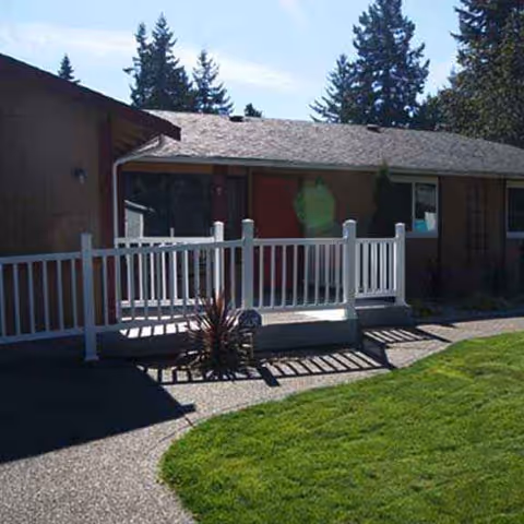 Front exterior of a single-story building with white railing and lawn.