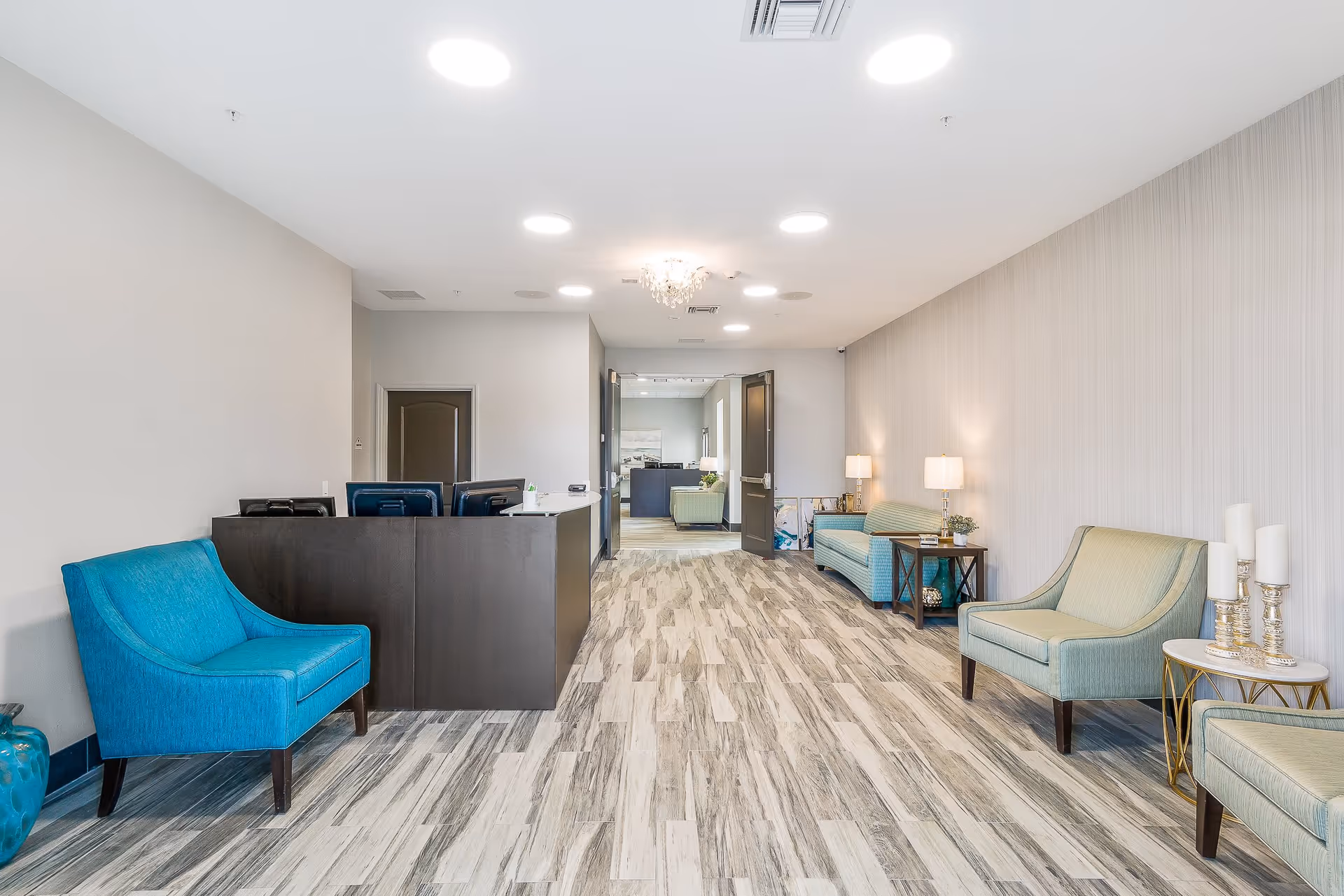 Bright modern assisted living reception lobby with a front desk, seating chairs and sofas, and decorative lighting.