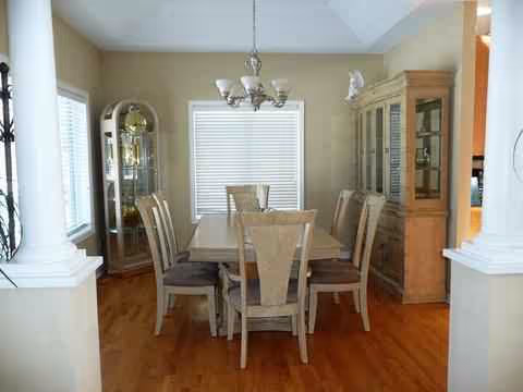 Dining room with rectangular table, six chairs, china cabinet, and chandelier.