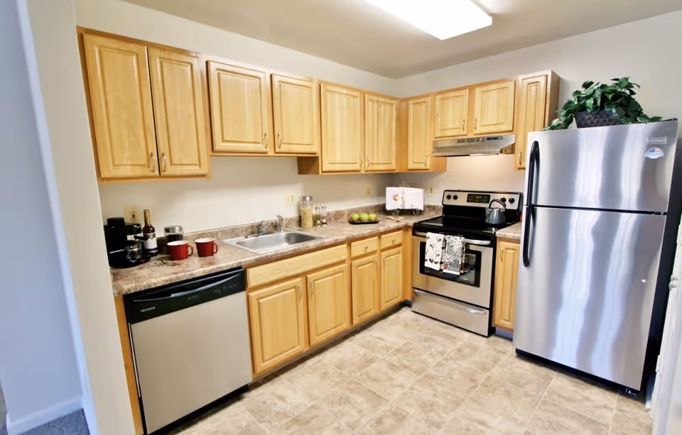 Kitchen with light wood cabinets, stainless steel refrigerator and stove, sink, and dishwasher.