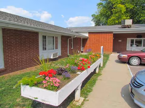 Exterior view of a brick senior living facility with flower planters.