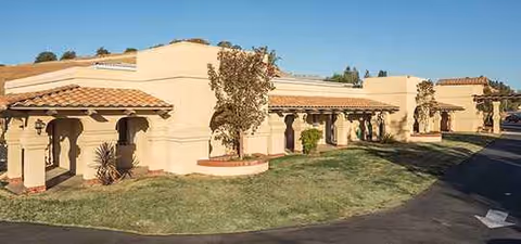 Exterior view of a beige stucco senior living building with arches.