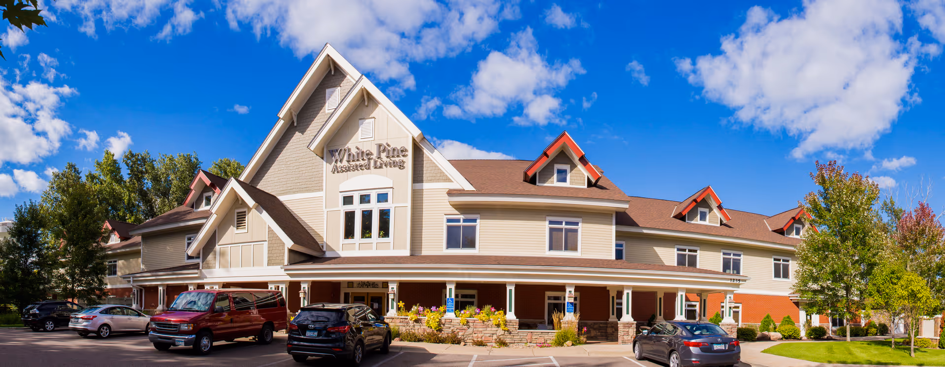 Front view of White Pine Senior Living building in White Bear Lake with cars.