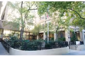 Exterior view of a senior living building entrance with trees and walkway.