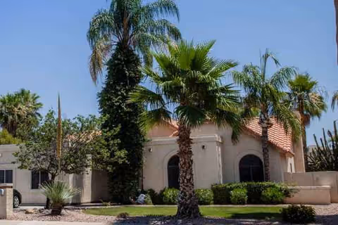 Front exterior of a beige senior living facility with palm trees and a tiled roof