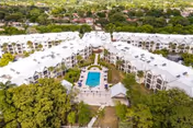 Aerial view of the Veranda Club's U-shaped white senior living complex surrounding a central courtyard with a swimming pool and trees.