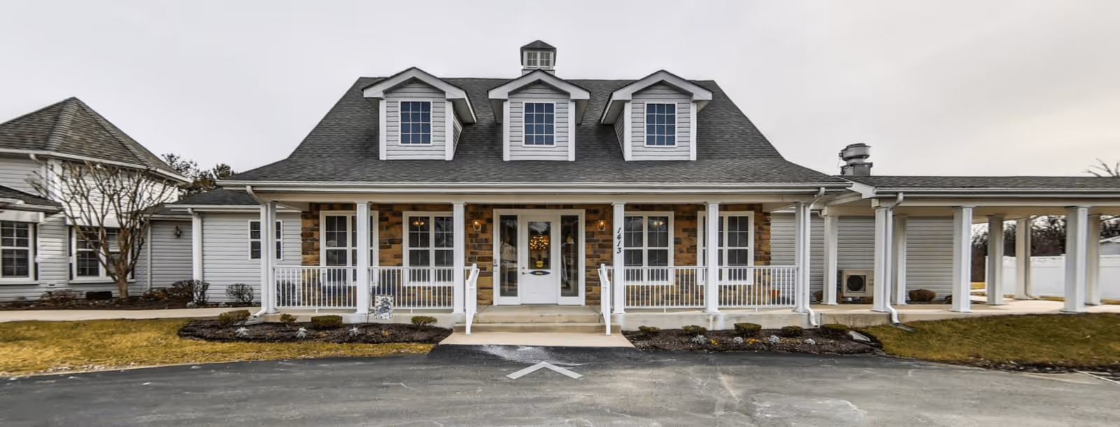 Front view of the Viva Senior Living at Bel Air building, showcasing a charming facade with a peaked roof, multiple windows, and a welcoming entrance surrounded by landscaped grounds.