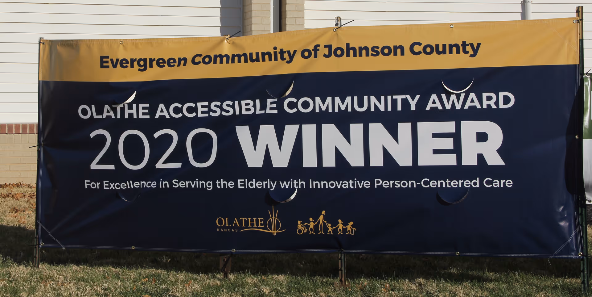 A large outdoor banner declaring Evergreen Community the 2020 Olathe Accessible Community Award winner.