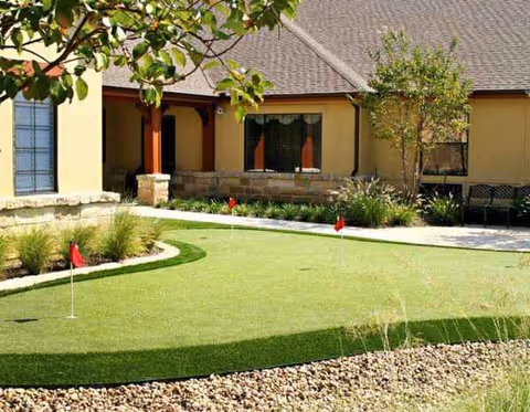Outdoor courtyard of a Prestonwood facility with a small putting green and landscaping.