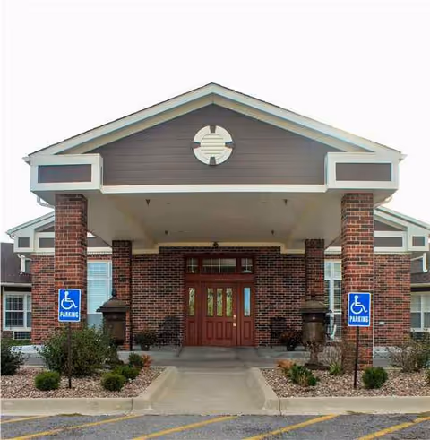 Front entrance of a senior living facility with brick columns and wheelchair signs.