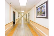 Bright, long hallway in a senior living facility with a framed painting on the wall.