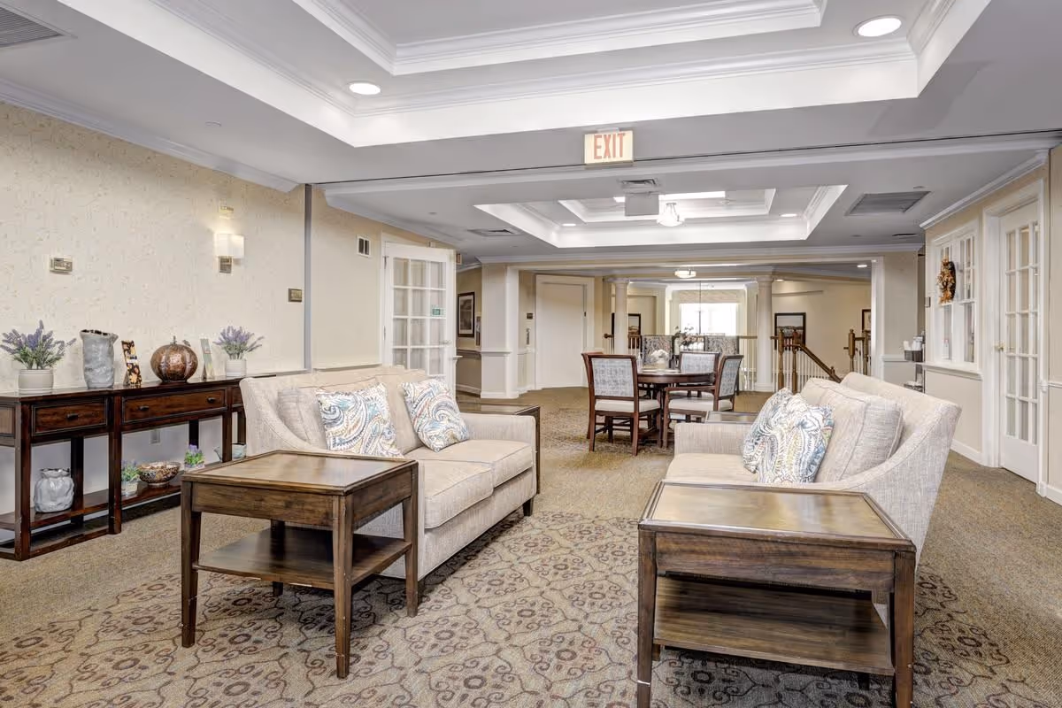 Spacious lounge with two beige sofas, wooden end tables, a console table, and a dining table under recessed tray ceilings.