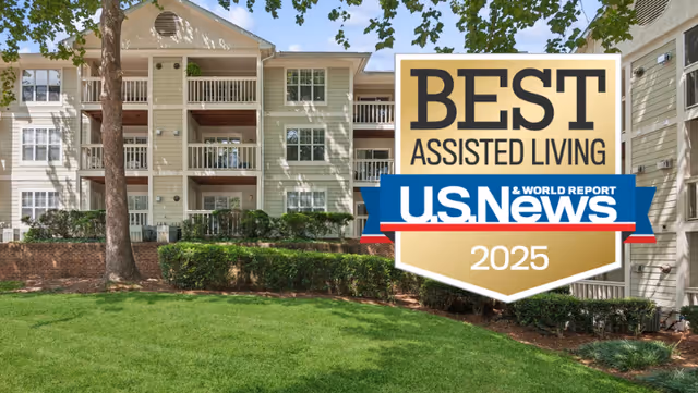 Three-story assisted living building with balconies, a manicured lawn, and a large 'Best Assisted Living U.S. News 2025' badge overlaid on the image.
