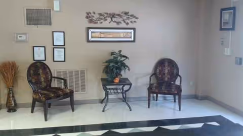 A quiet lobby seating area with two patterned chairs and a small table.