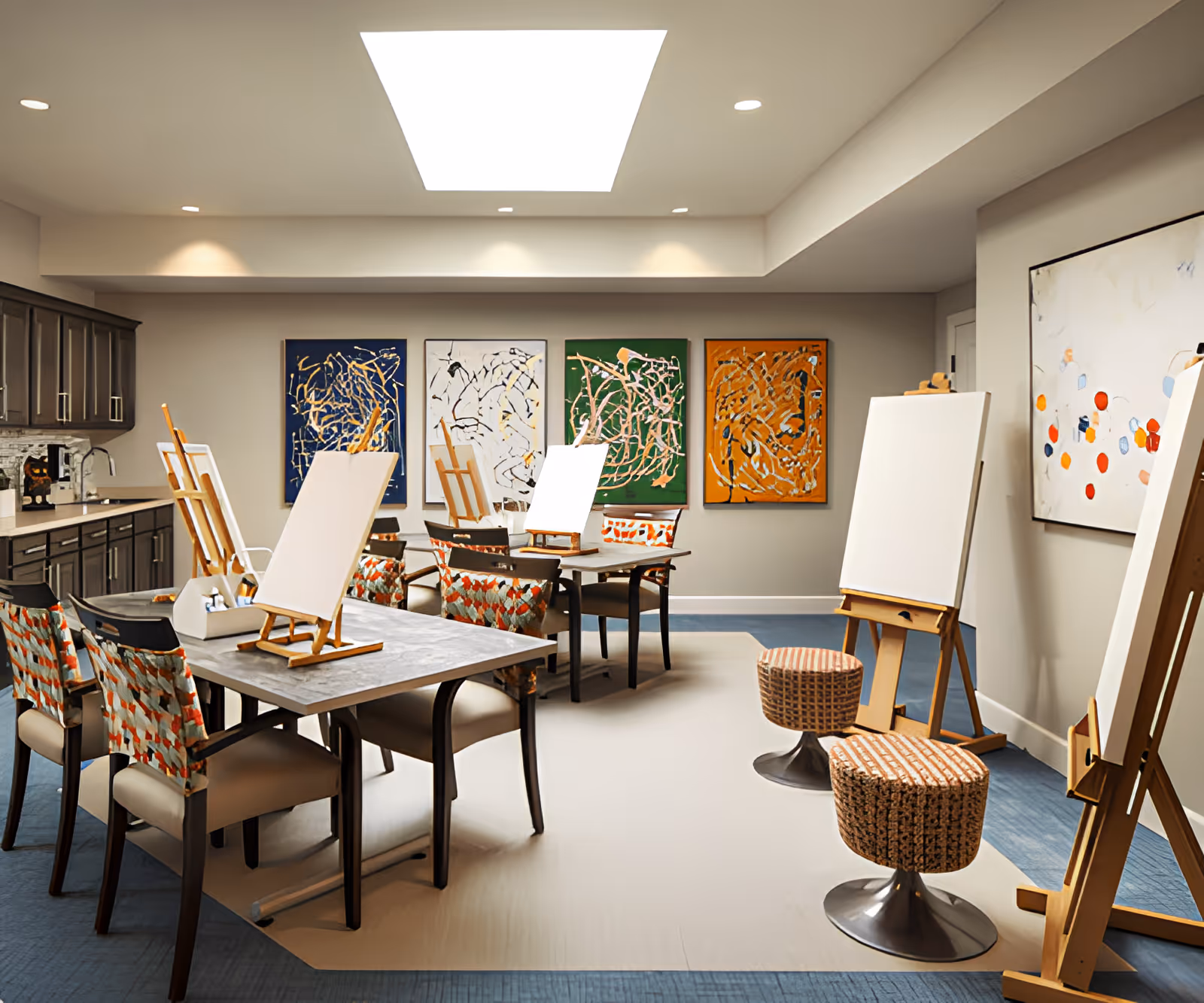 Bright art studio/activity room with easels, tables, chairs, and colorful abstract paintings on the walls.