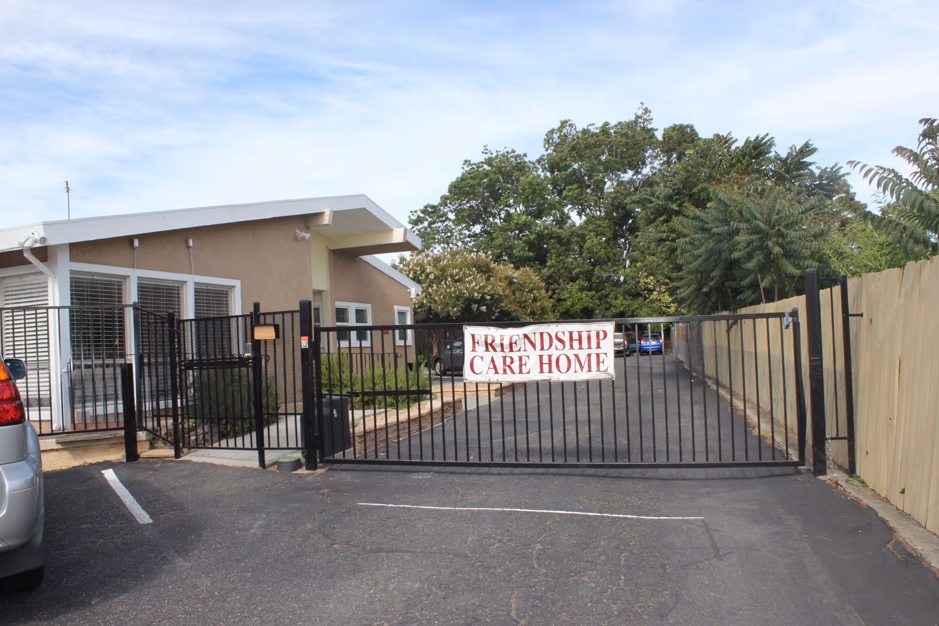 Front exterior of Friendship Care Home showing a gated driveway and a single-story building with a sign on the gate.