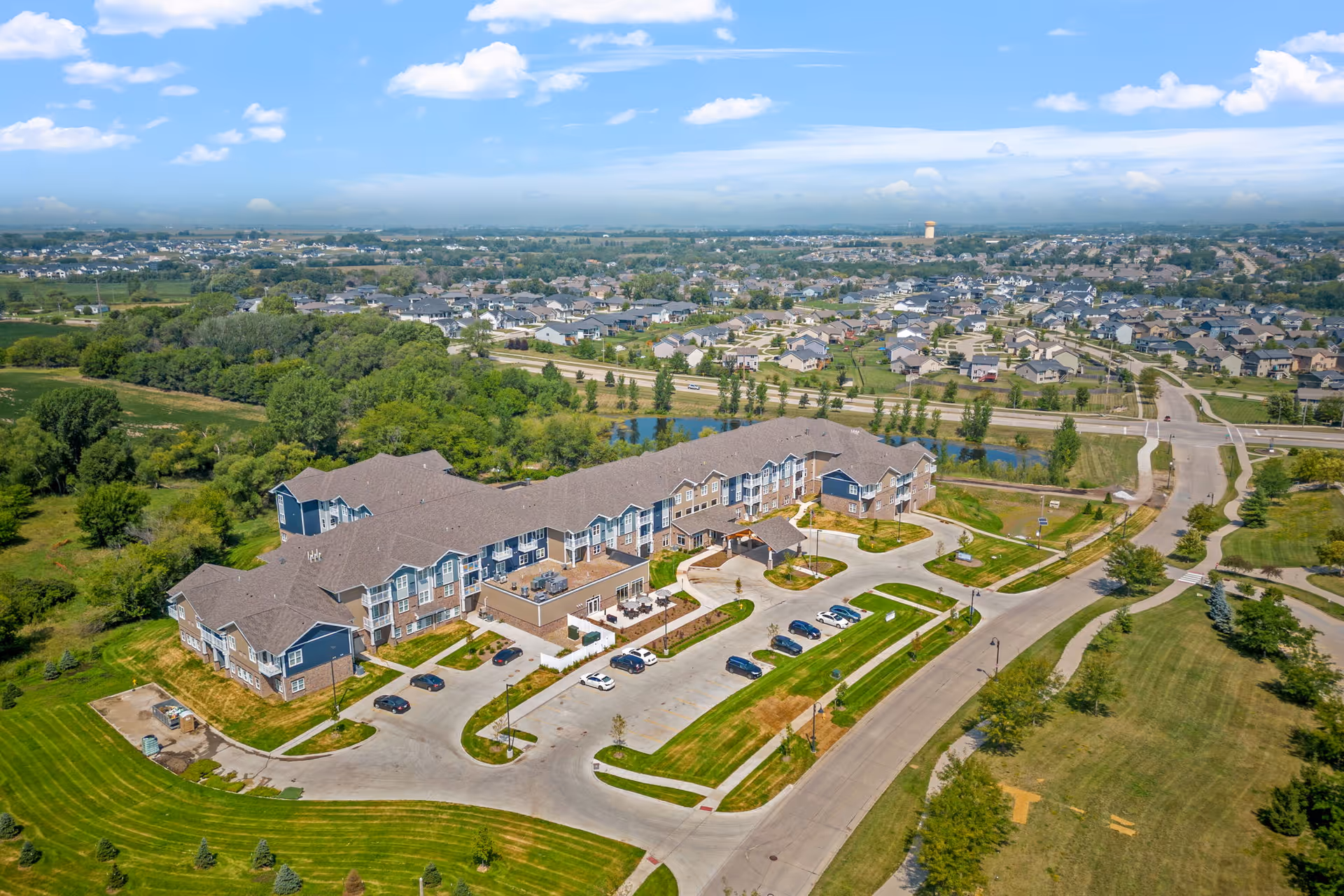 Aerial view of the Meadowview of Clive senior living facility with surrounding lawns, parking areas, and nearby residential neighborhood.