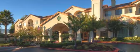 Exterior view of Oakmont of Montecito, a senior living community, with arches, palms, and landscaped entrance.