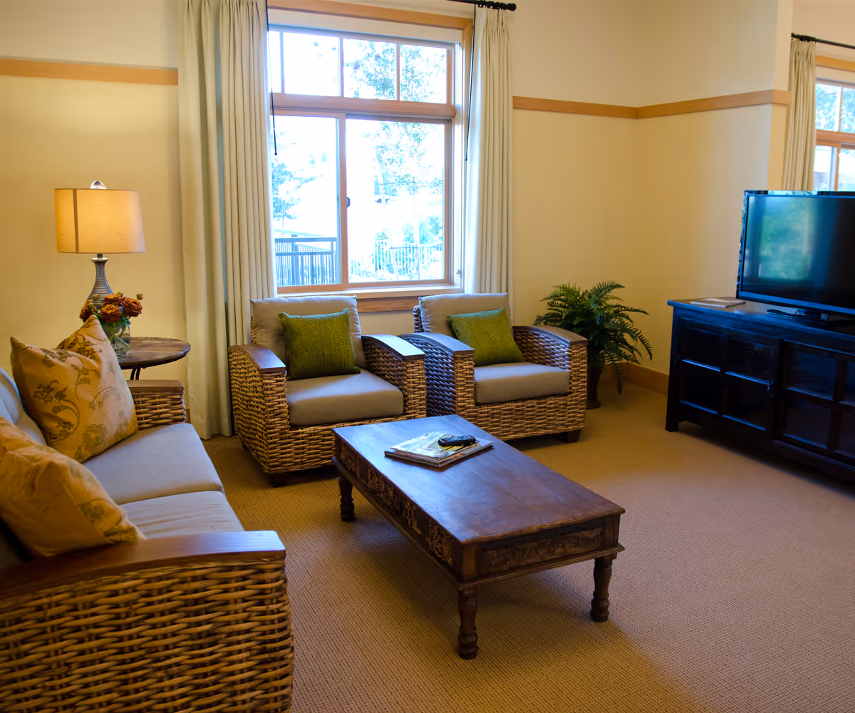 Cozy living room with wicker seating, a coffee table, and a TV.