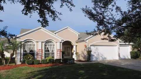 Front view of a beige senior living facility with a two-car garage and landscaped yard.