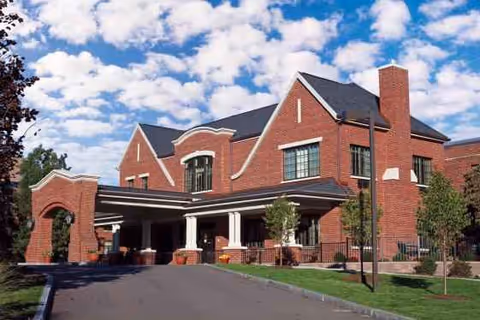 Front view of a brick senior living facility with a covered entrance.