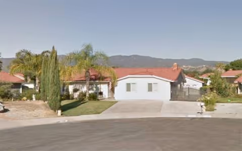 Exterior view of a single-story facility with white walls and red roof.
