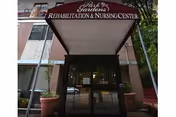 Front entrance of Park Gardens Rehabilitation & Nursing Center with a maroon awning and glass double doors.