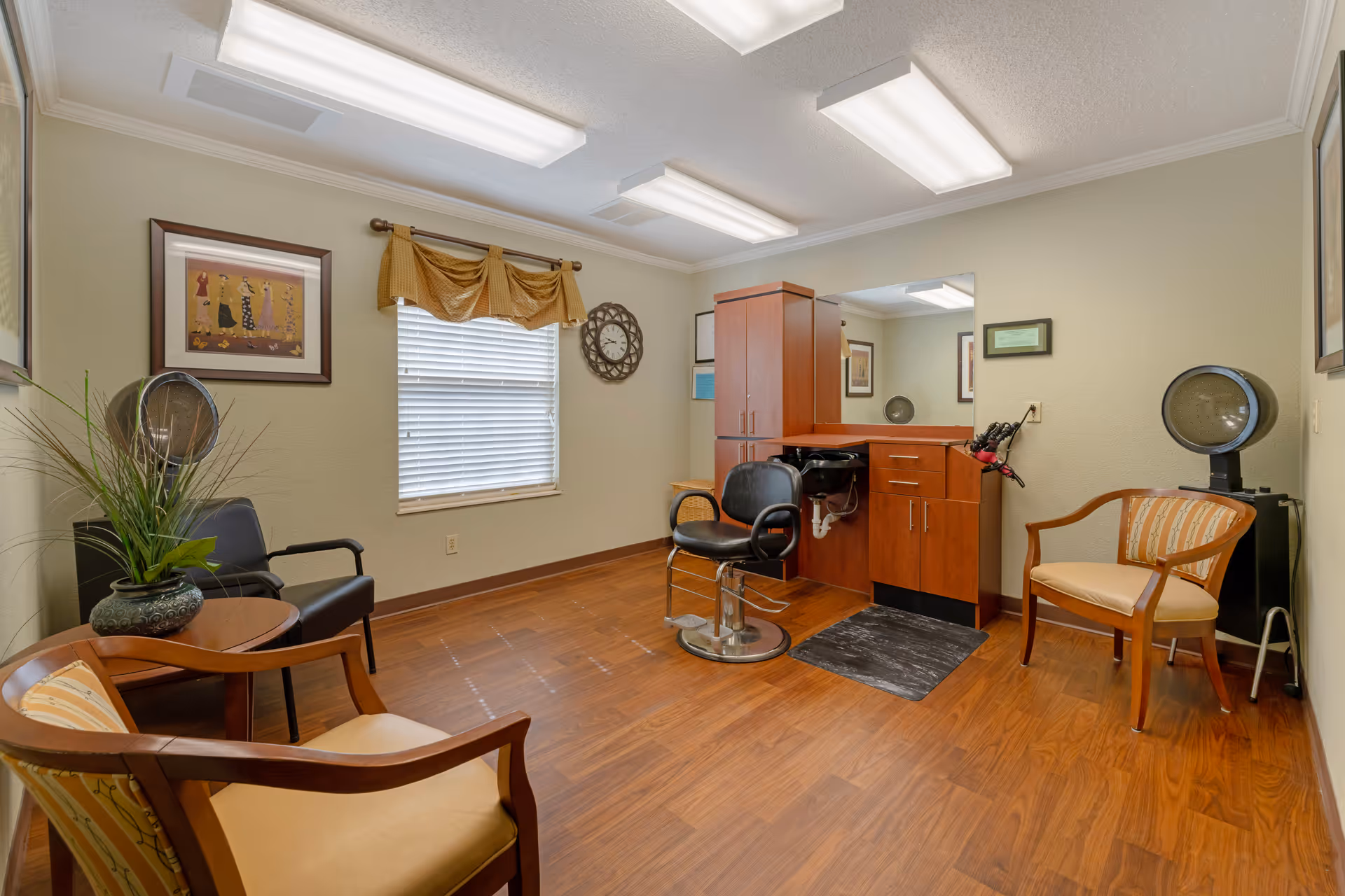 Small salon-style room with a styling chair, hair dryer stations, cabinets, and several chairs.